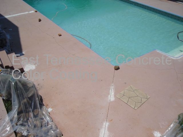 A swimming pool is surrounded by a pink concrete deck