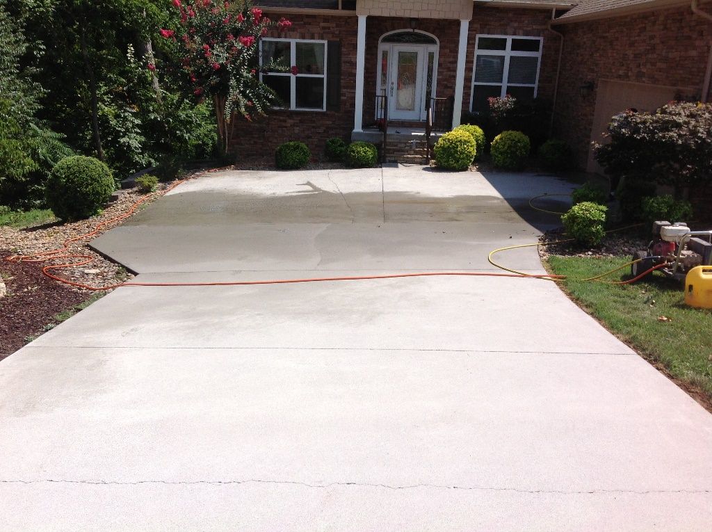 A brick house with a concrete driveway in front of it.