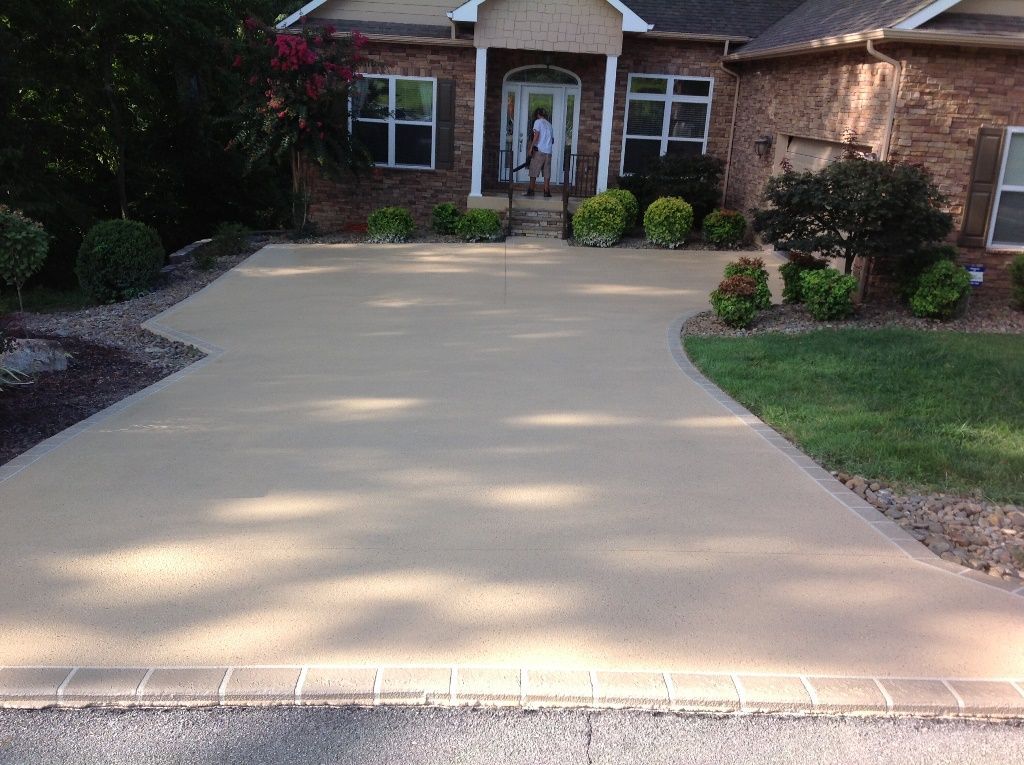 A brick house with a concrete driveway in front of it.