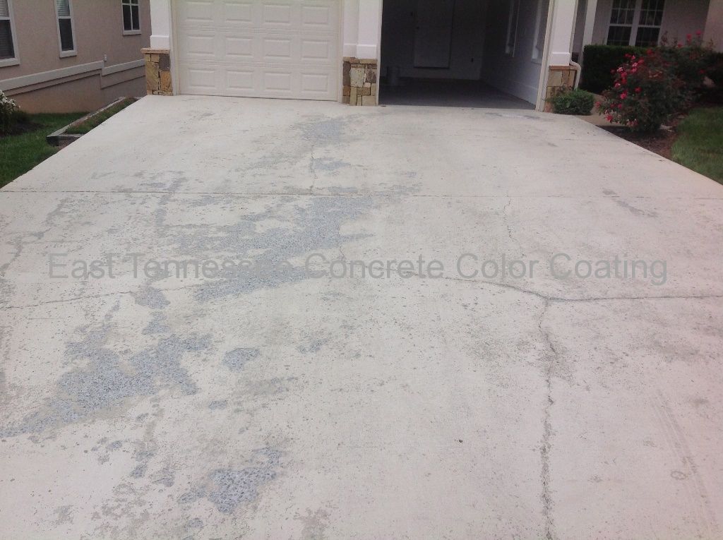 A concrete driveway in front of a house with a garage door.