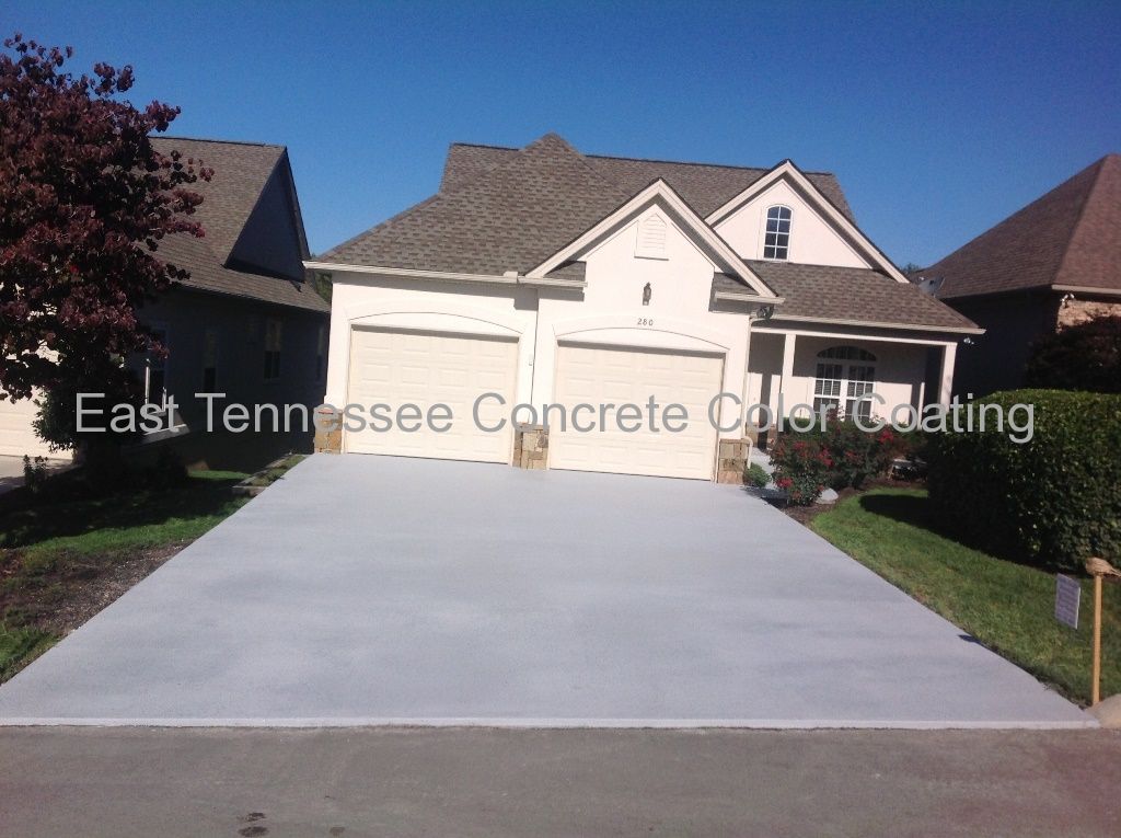 A white house with a concrete driveway in front of it