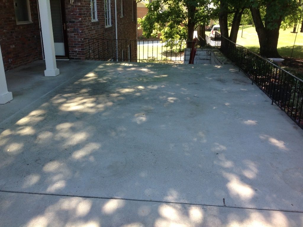 A concrete driveway with a brick house in the background