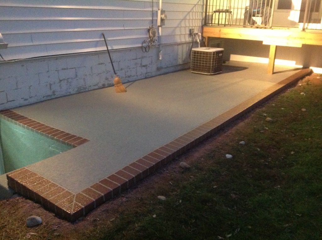 A patio with a pool in the background and a broom in the foreground