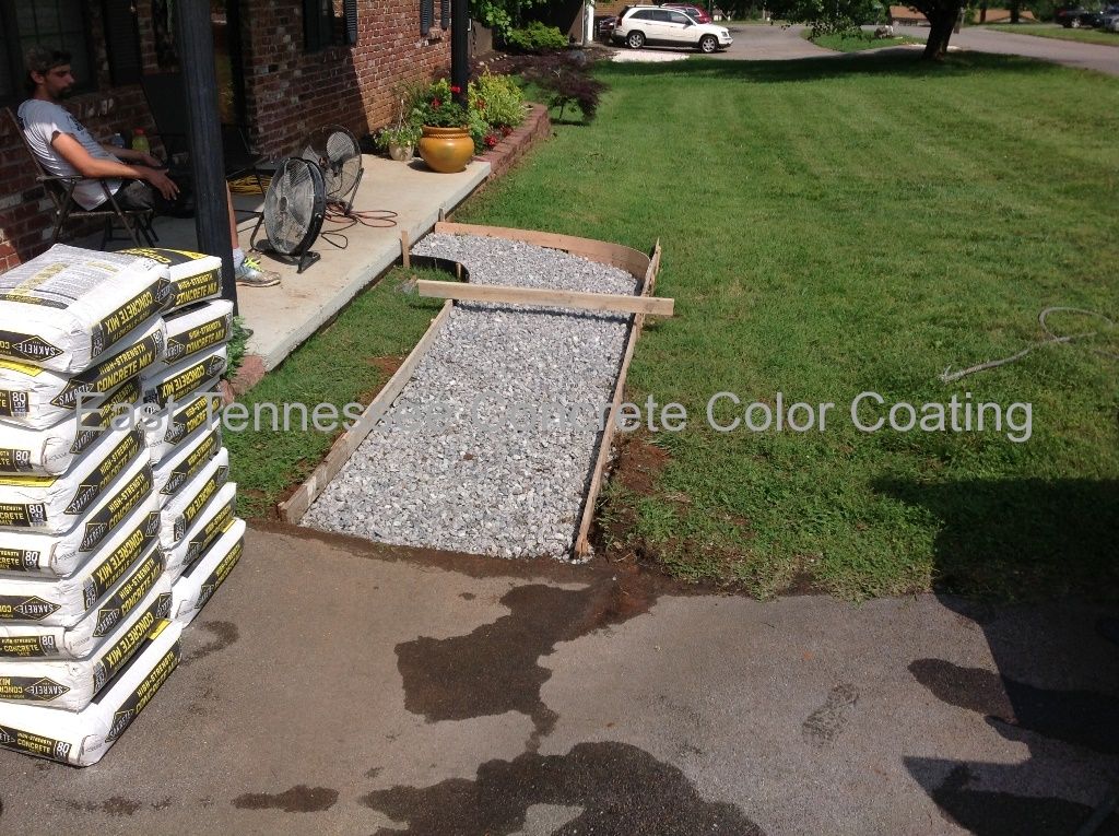 A man sits on a porch next to a pile of bags of concrete