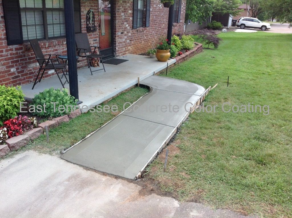 A concrete walkway is being built in front of a brick house.