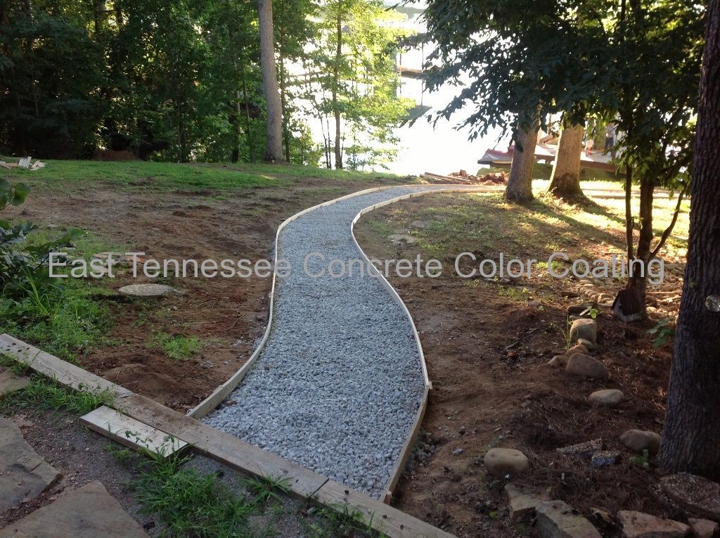 A concrete walkway is going through a lush green field.