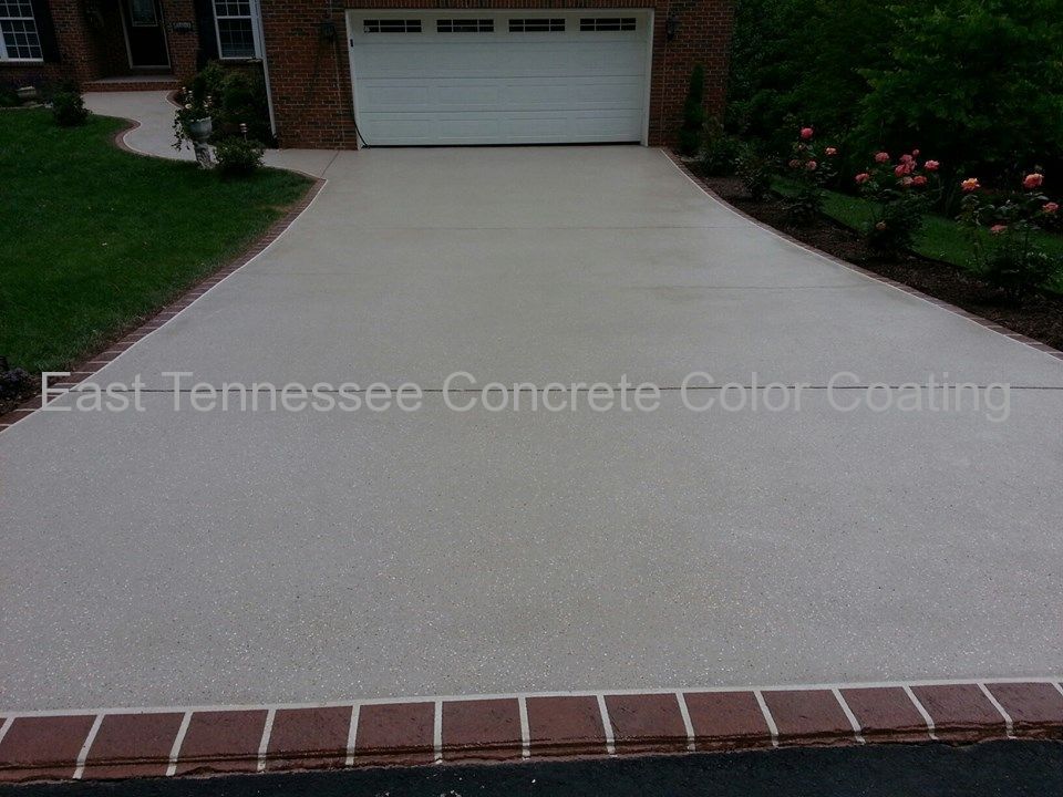 A concrete driveway with a white garage door and a curb.