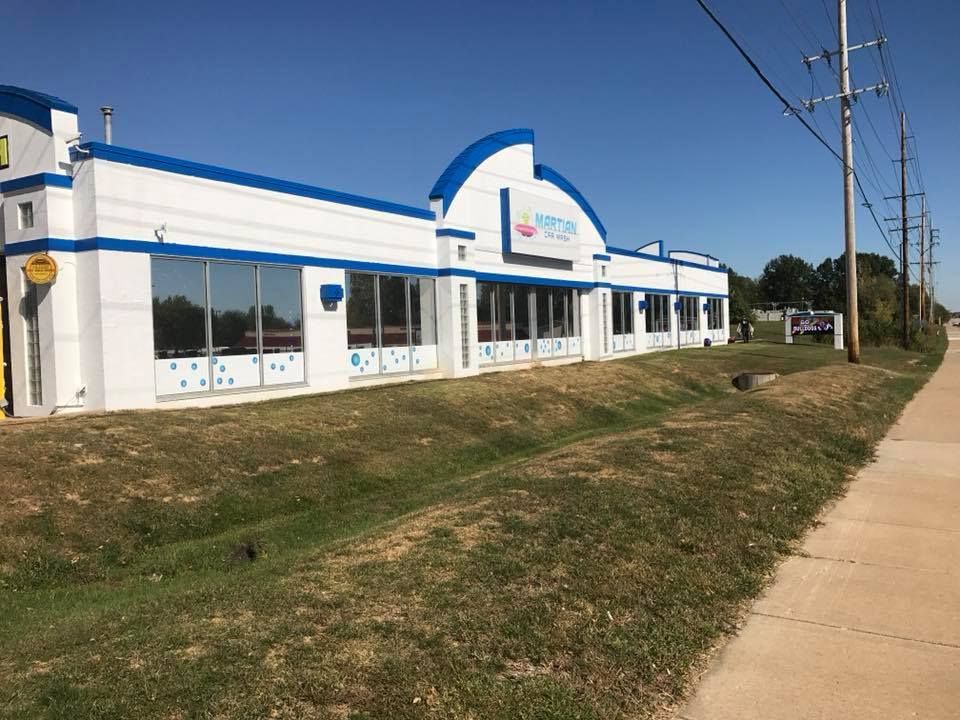 A large white and blue building with a sidewalk in front of it.