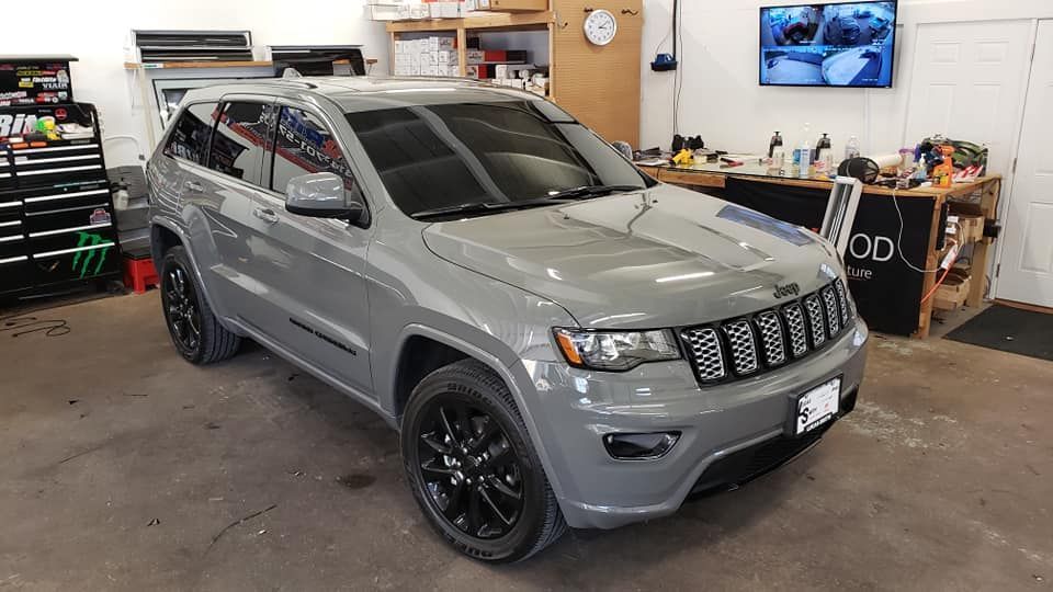 A gray jeep grand cherokee is parked in a garage.