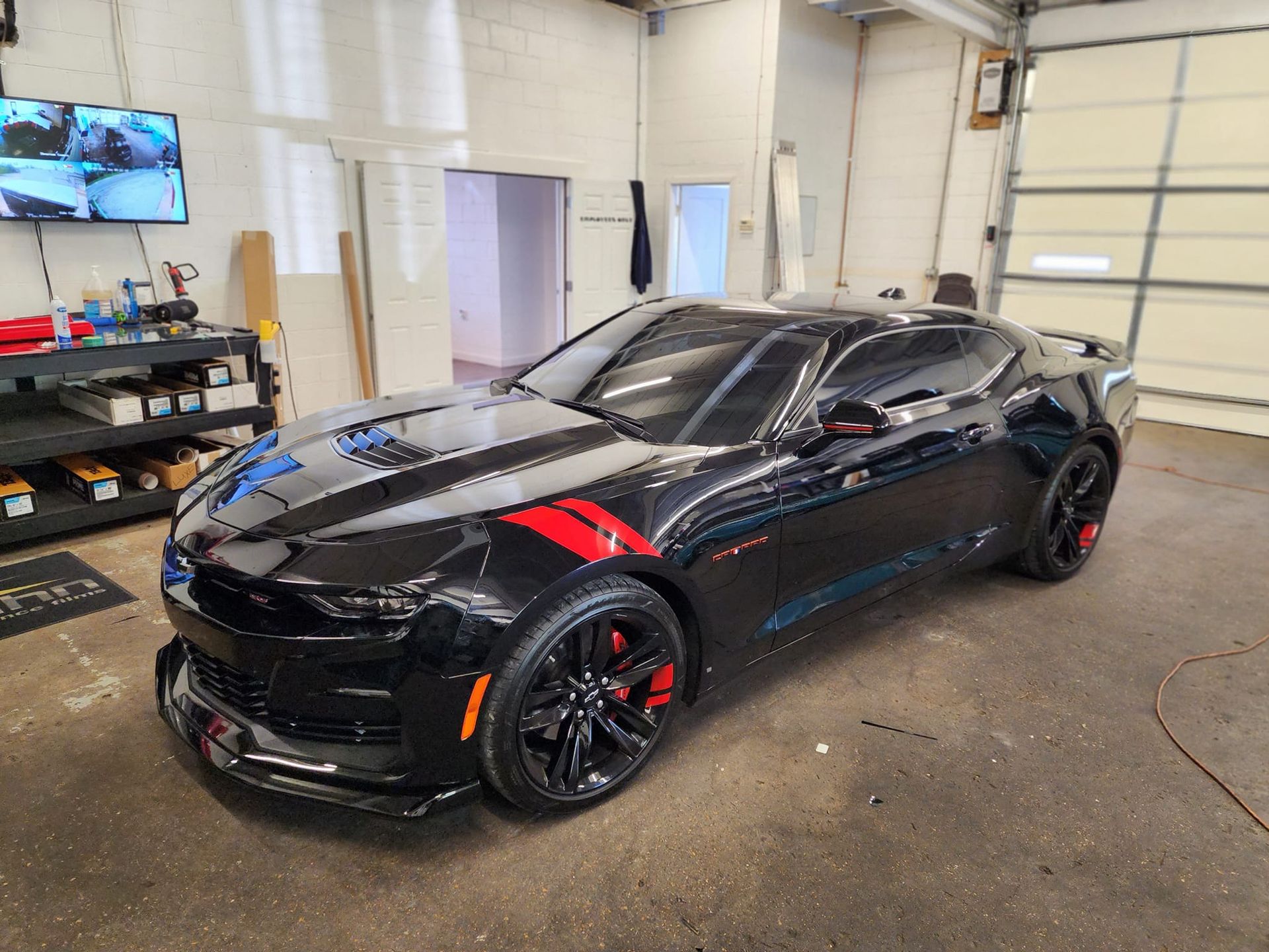 A black car with a red stripe on the side is parked in a garage.