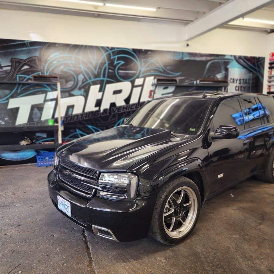 A black car is parked in front of a sign that says tintrite