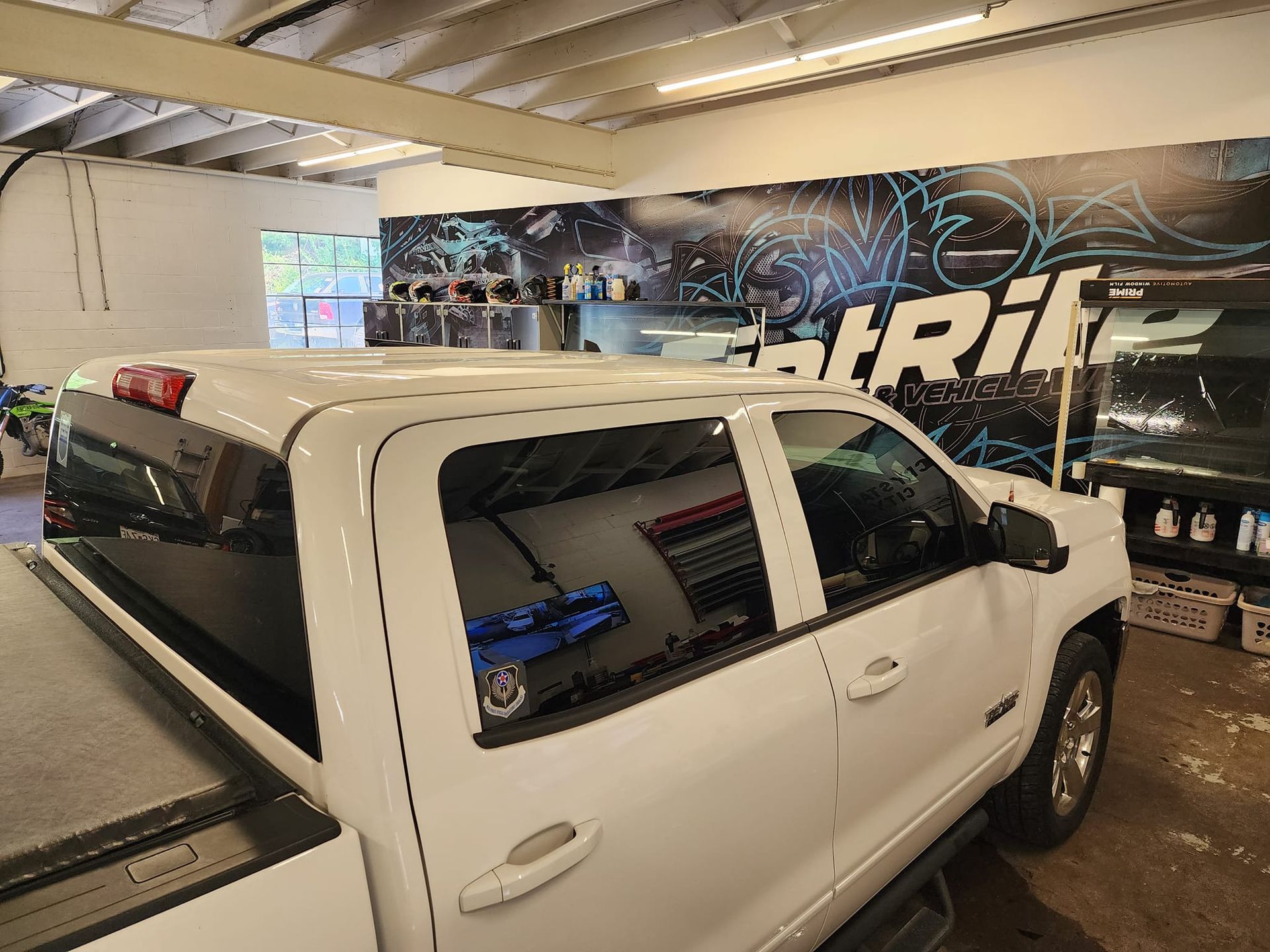 A white truck is parked in a garage with a roof rack.