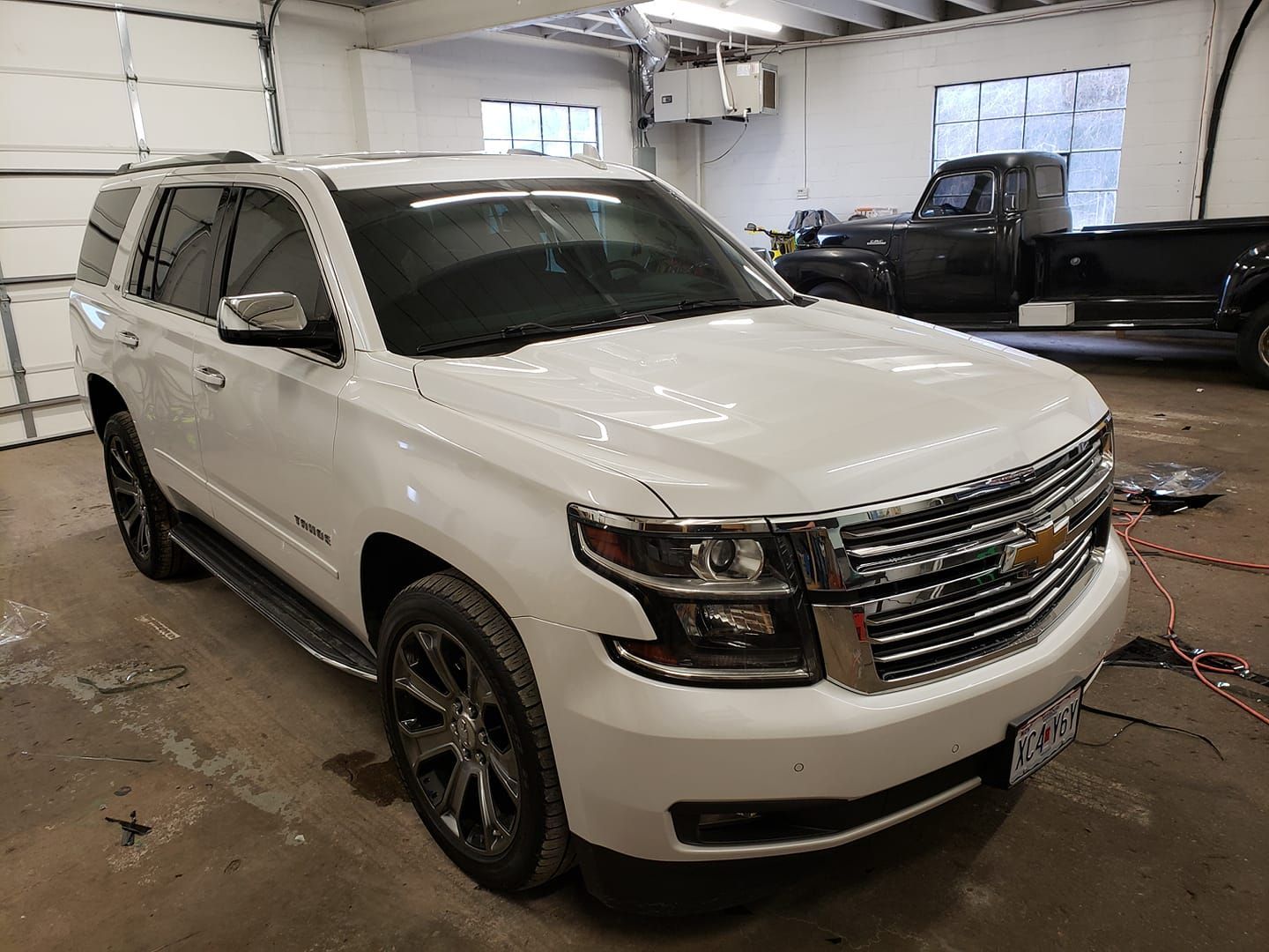 A white suv is parked in a garage next to a black truck.