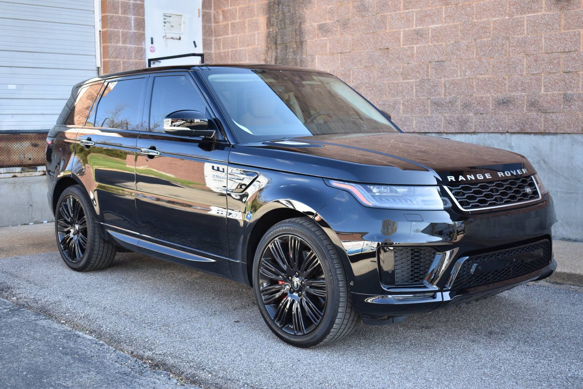 A black range rover sport is parked in front of a brick building.