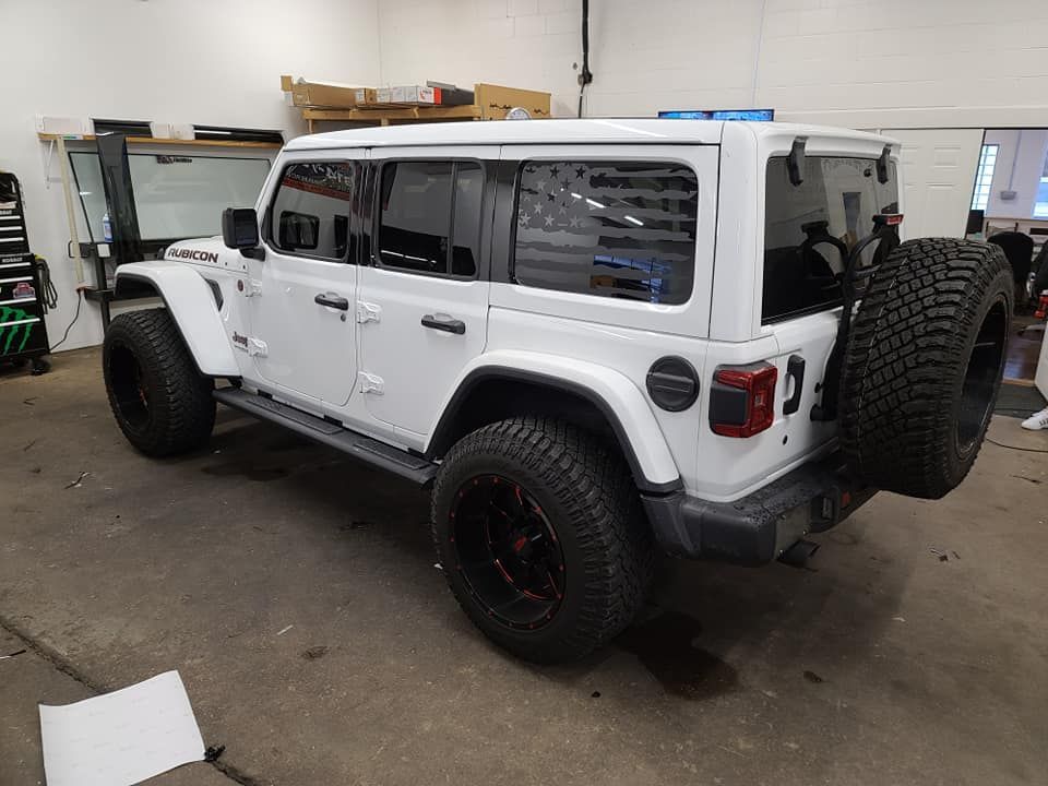 A white jeep wrangler is parked in a garage.