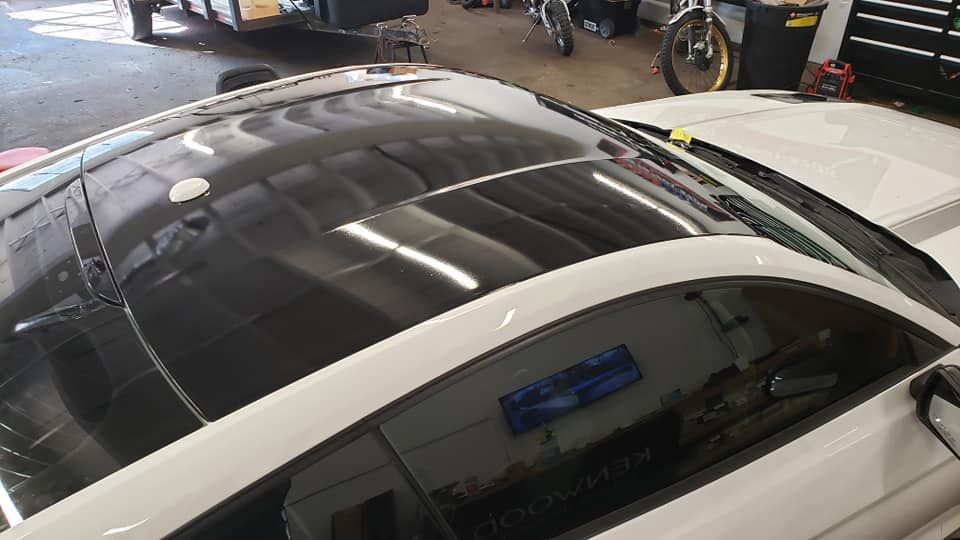 A white car with a black roof is parked in a garage.