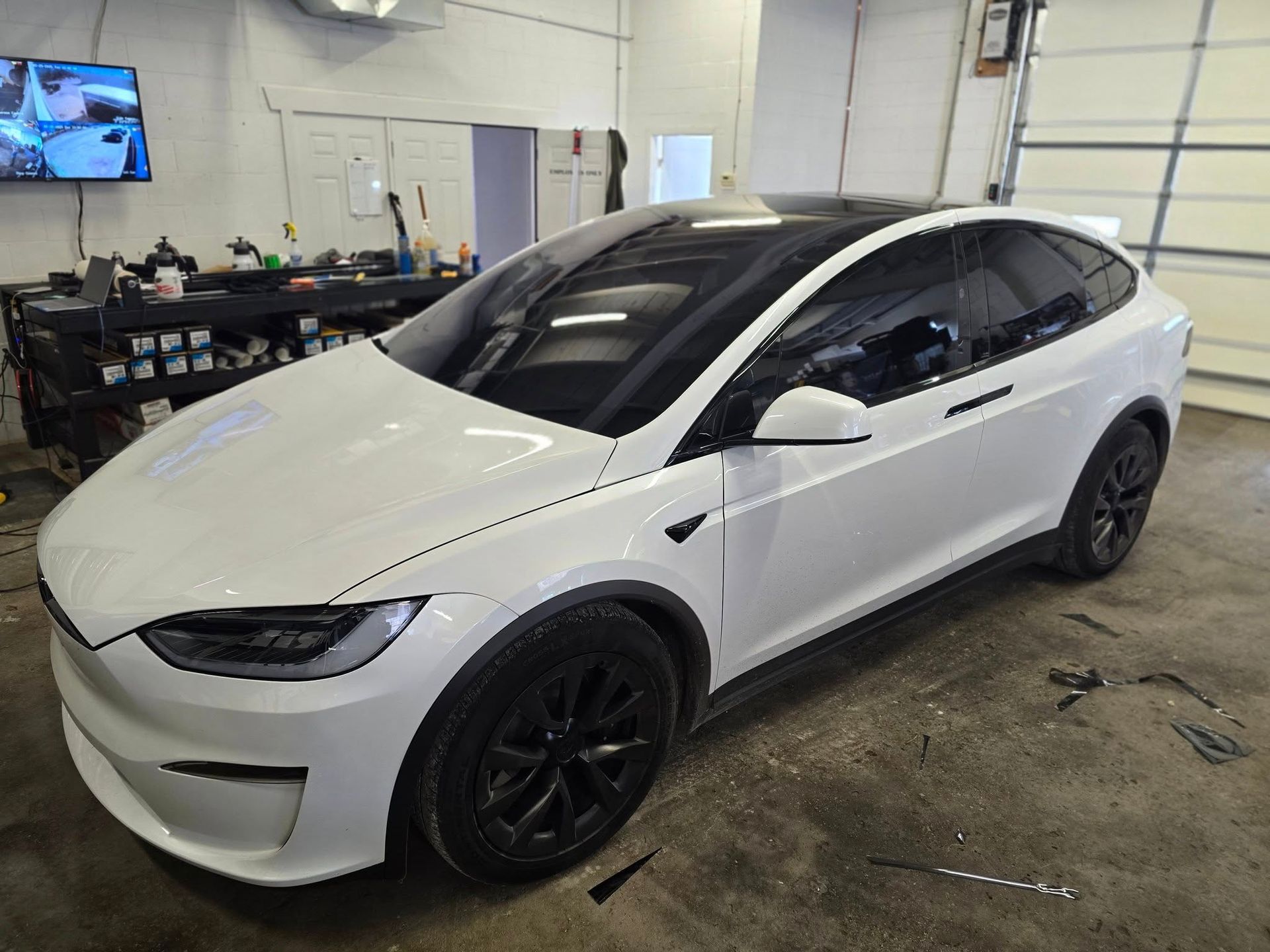 A white tesla model x is parked in a garage.