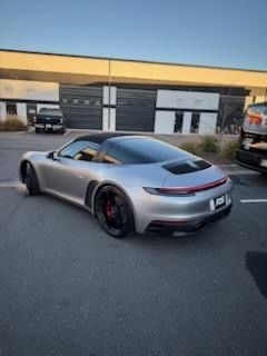 Silver Porsche 911 Targa parked outdoors, with black roof and red accents on wheels.