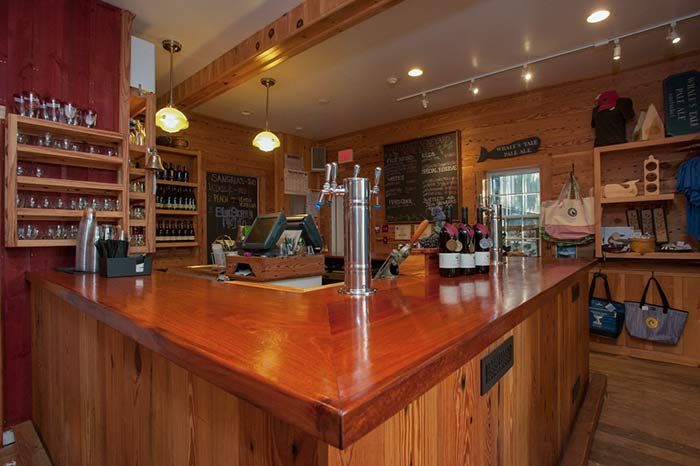 A wooden bar in a restaurant with bottles of wine on it.