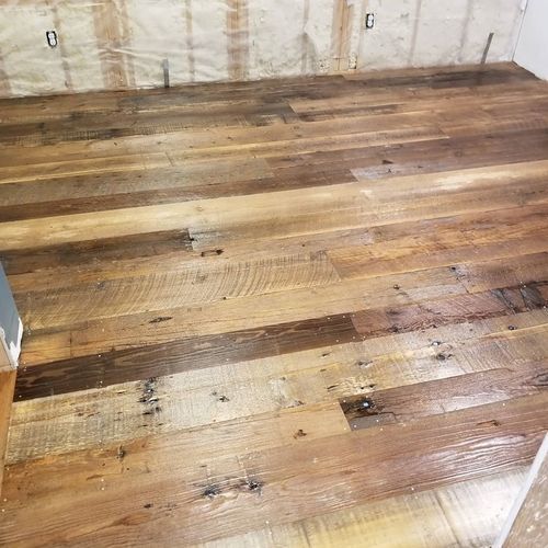 A wooden floor in a room with a wall behind it.