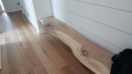 A wooden bench is sitting in a hallway next to a white wall.