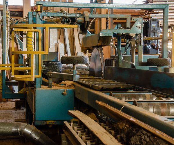 A machine is cutting a piece of wood in a factory
