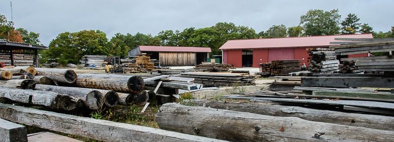 A pile of logs is sitting in front of a building.