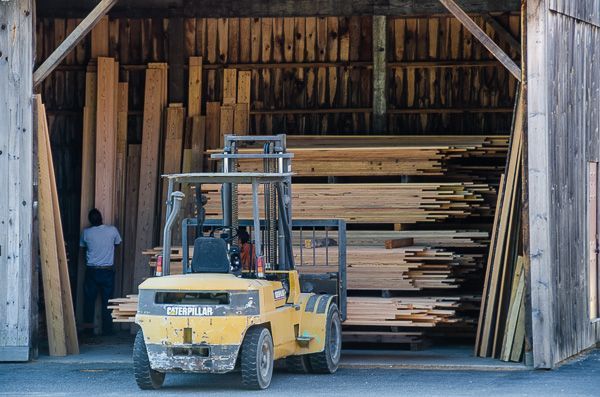 A yellow forklift is loading wood into a warehouse