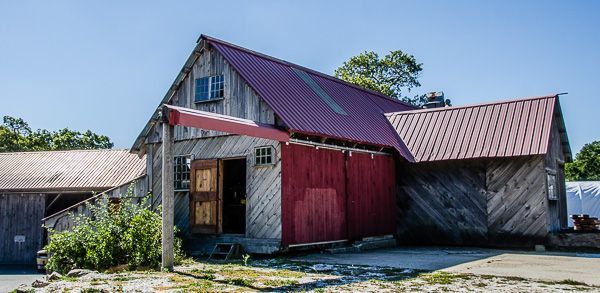 A wooden barn with a red roof and a red awning.
