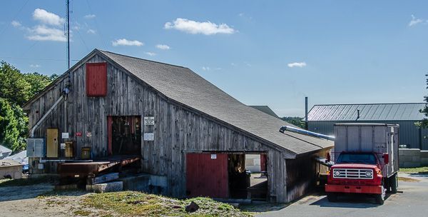A red truck is parked in front of a wooden building.
