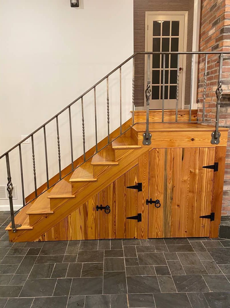 A wooden staircase with a metal railing and a wooden door underneath it.