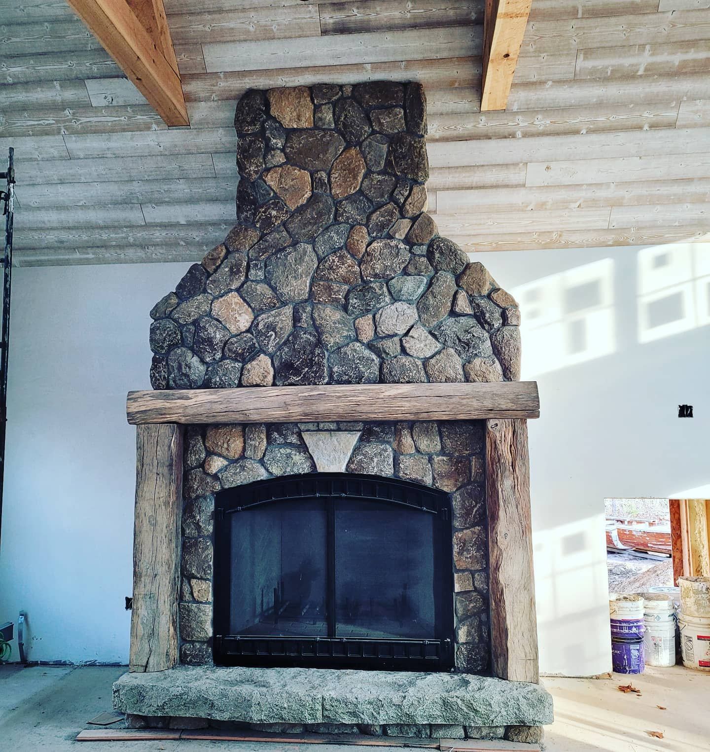 A stone fireplace in a room with a wooden ceiling