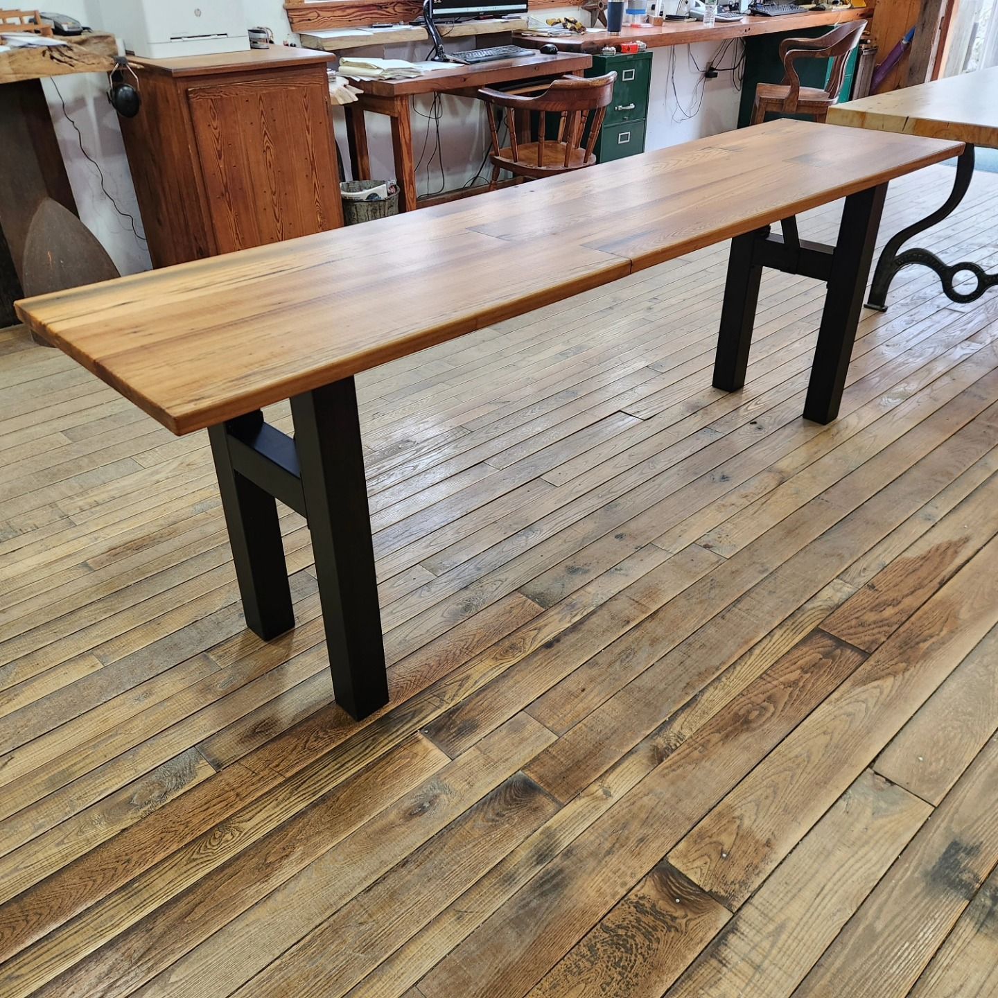 A wooden bench is sitting on a wooden floor in a room.
