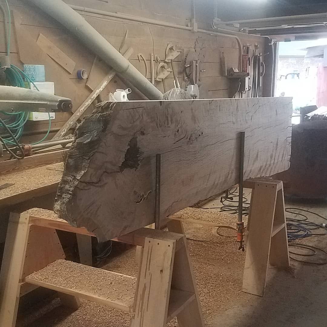 A large piece of wood is sitting on top of a wooden ladder in a workshop.