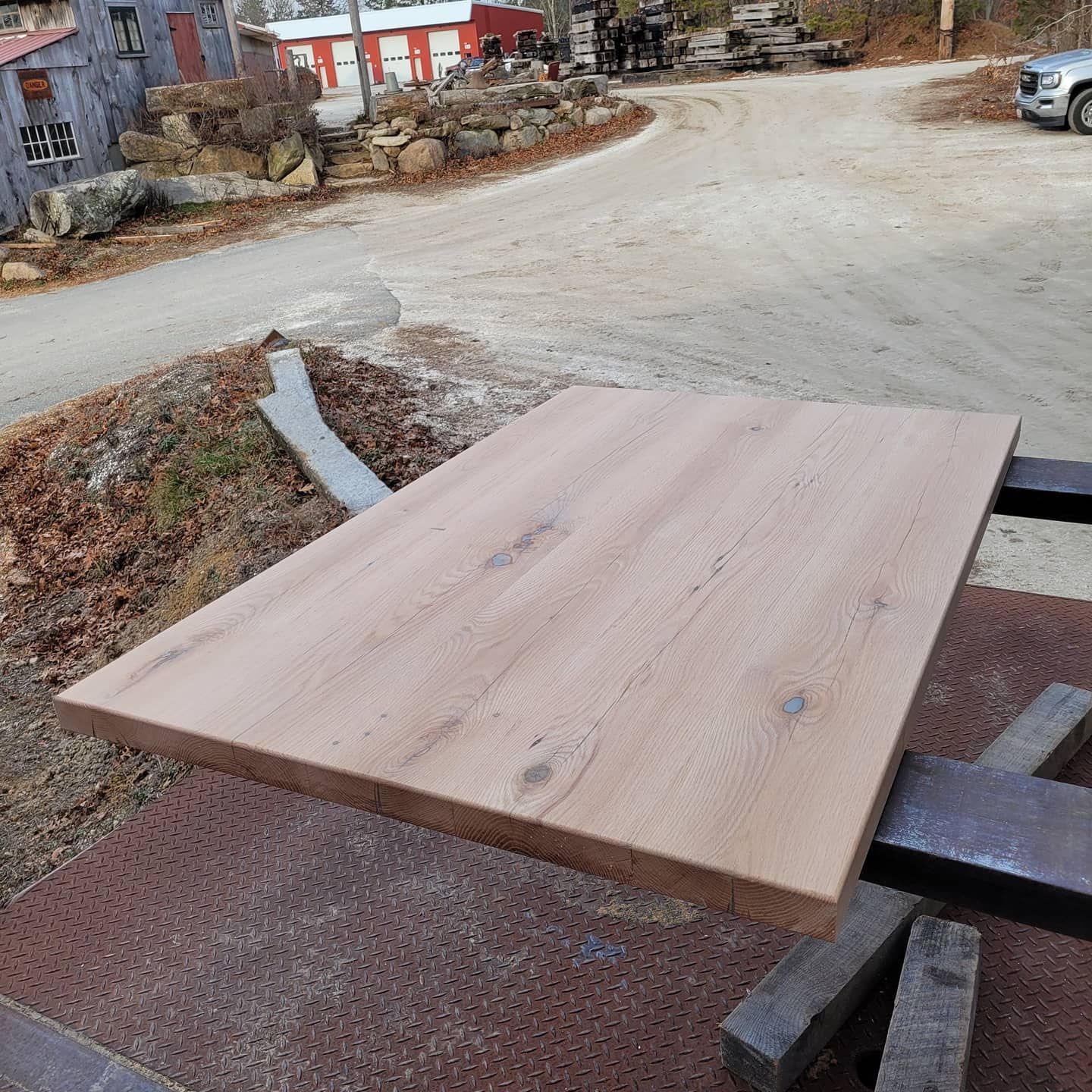 A wooden table is sitting on top of a dirt road.
