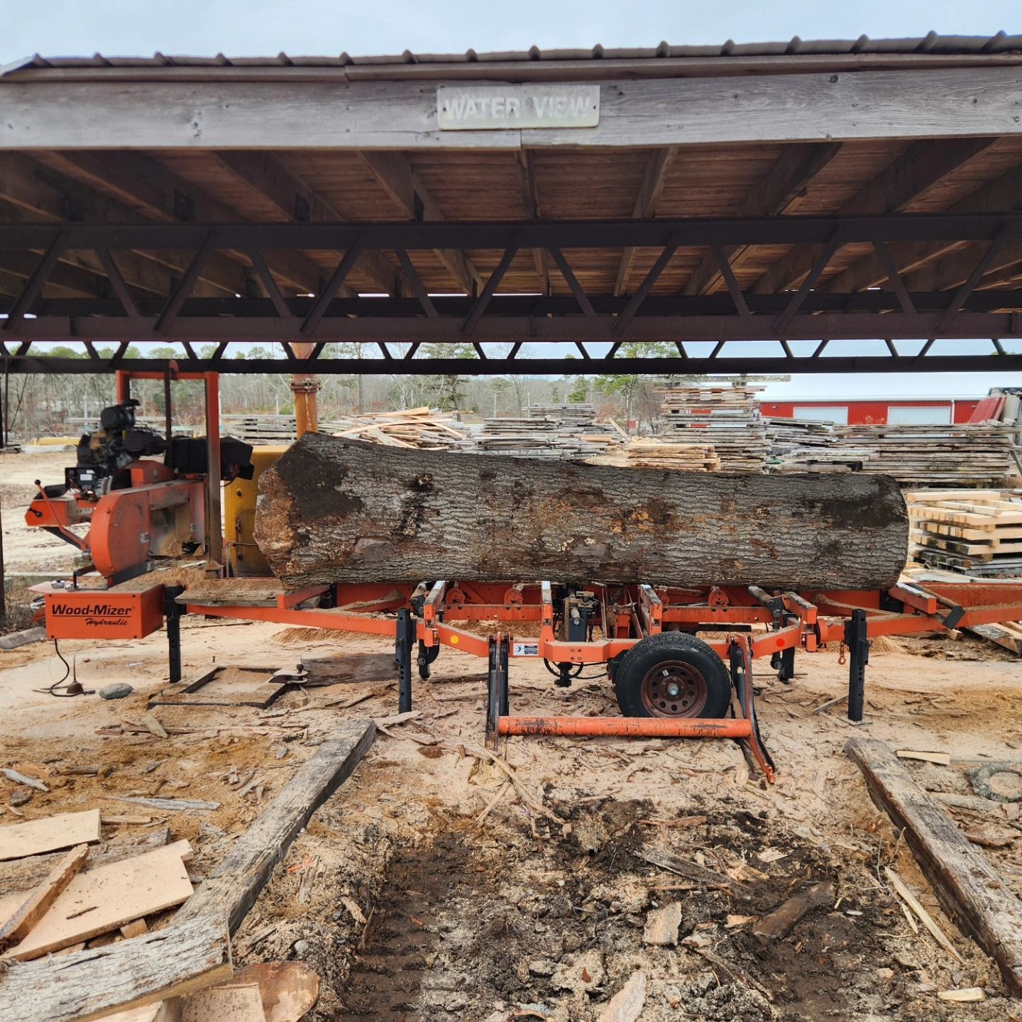 A large log is being cut by a portable sawmill