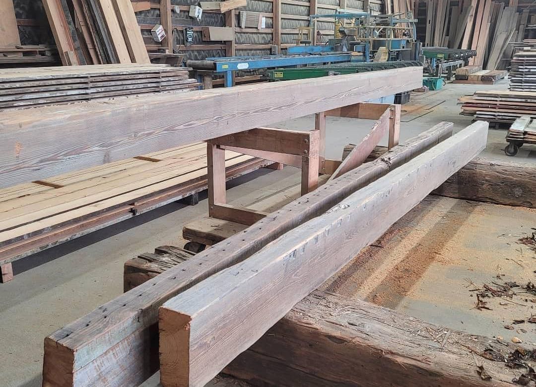 A bunch of wooden beams are sitting on top of each other in a warehouse.