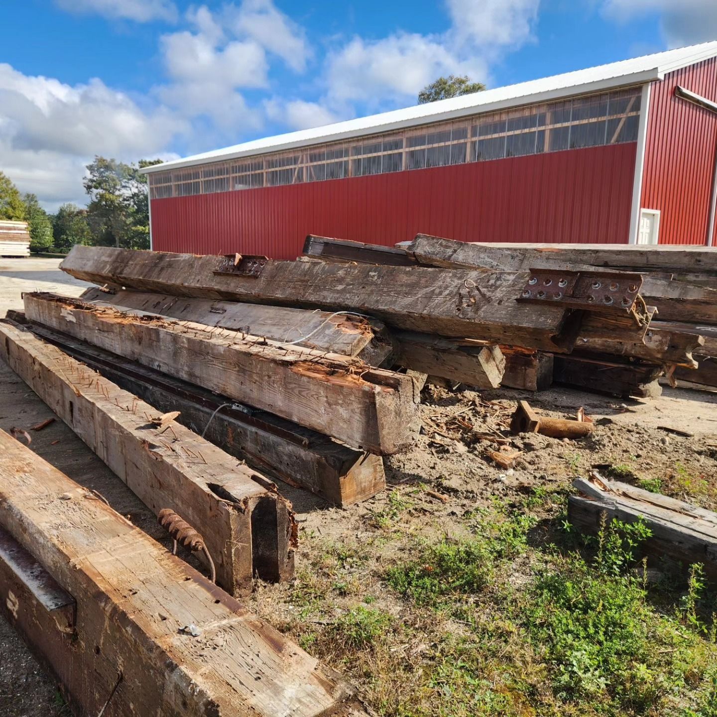 A pile of wood is sitting in front of a red building