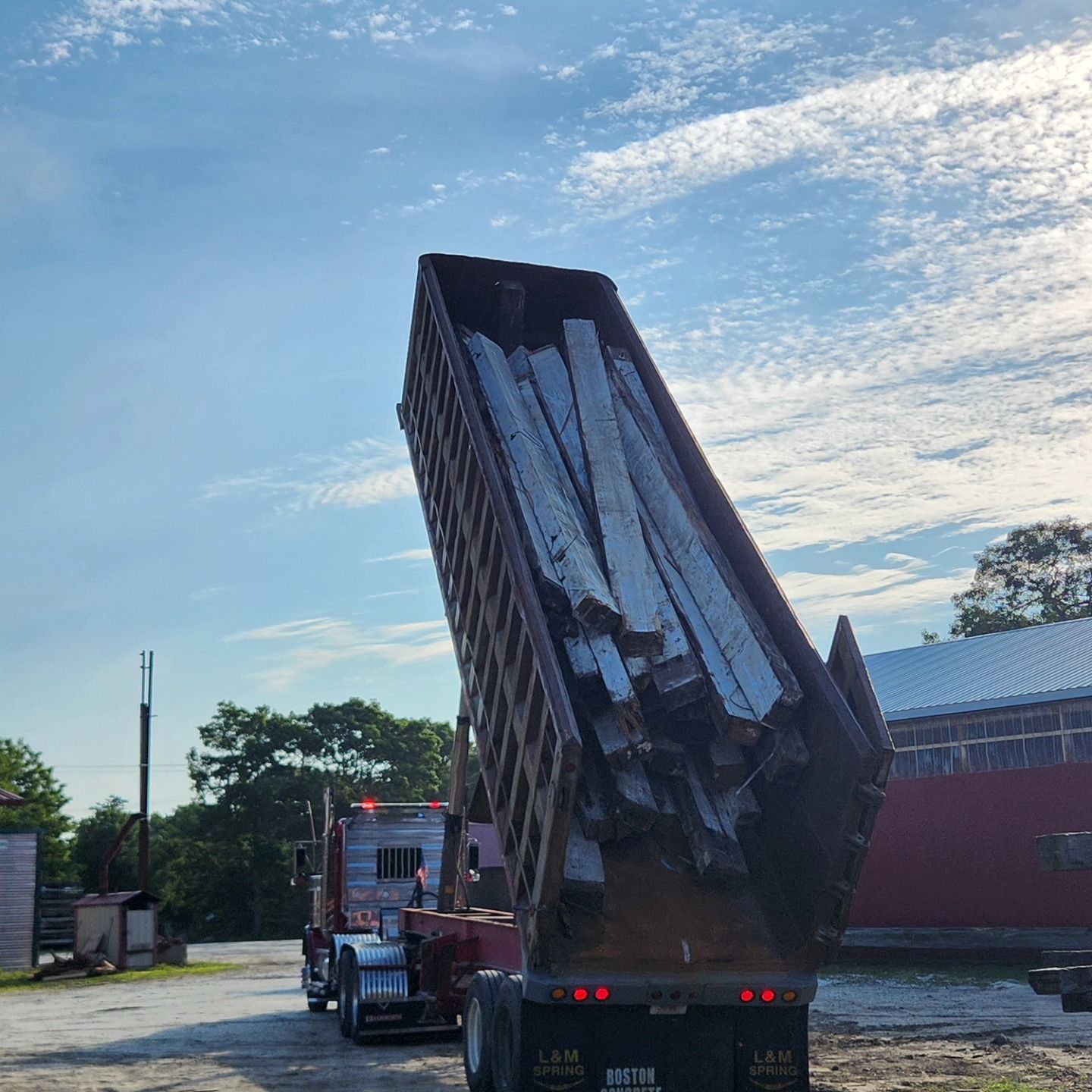 A dump truck is loaded with a large container of wood.
