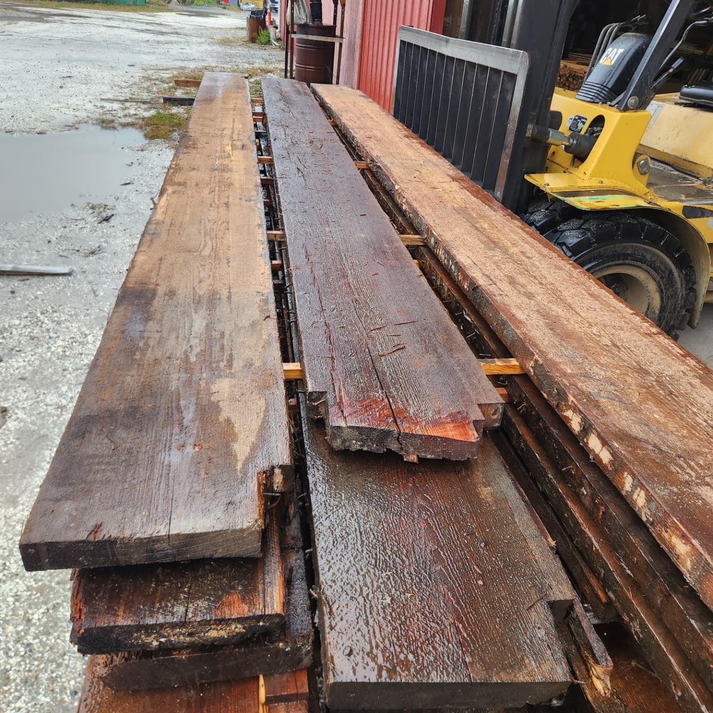 A stack of wooden boards with a forklift in the background.