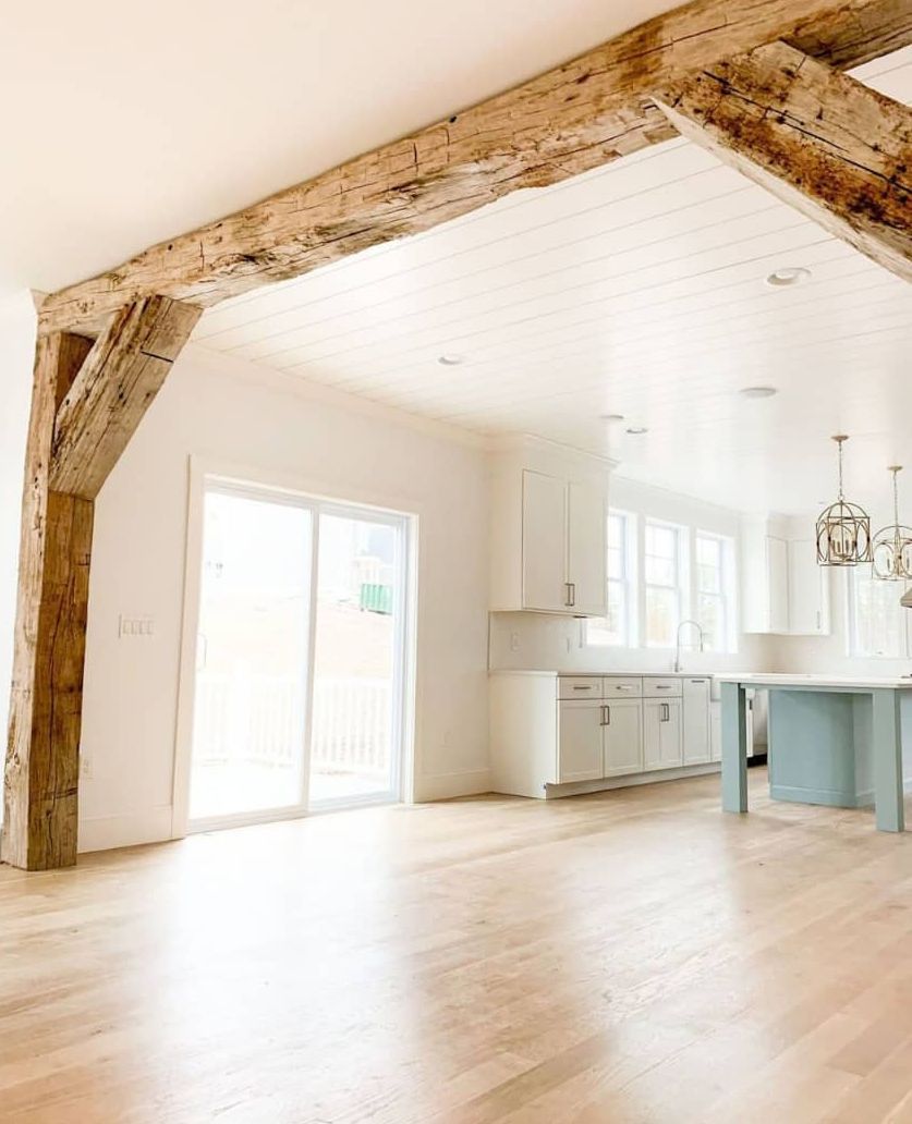 An empty kitchen with wooden beams and sliding glass doors.