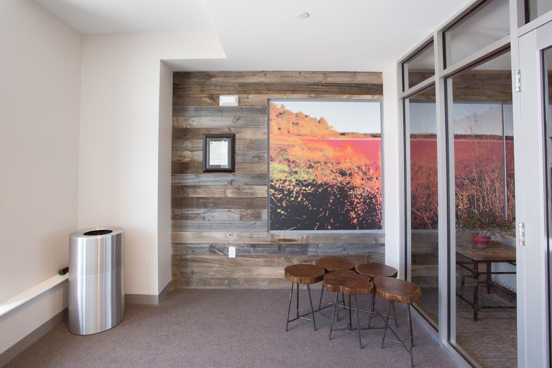 A room with a picture on the wall and a trash can.