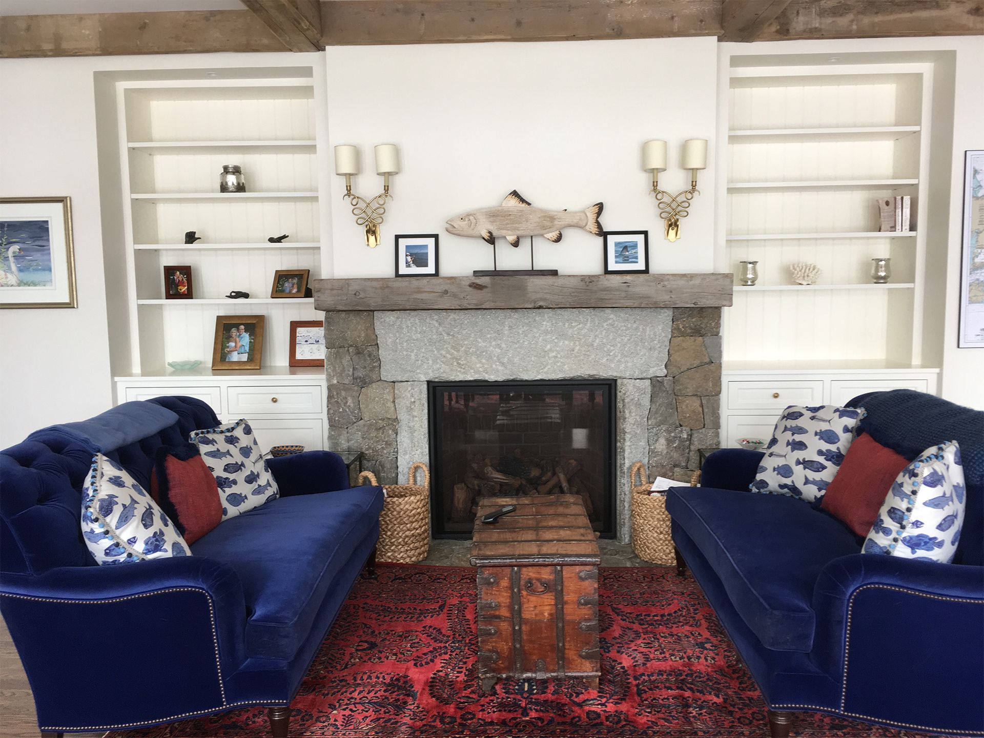 A living room with two blue couches and a fireplace