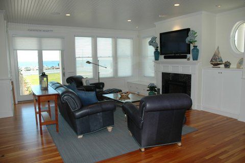 A living room with a couch , chairs , fireplace and television.