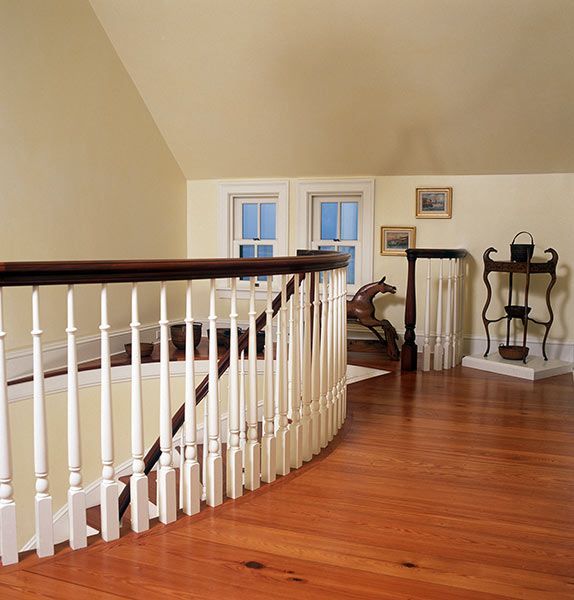 A staircase with a white railing and wooden floors