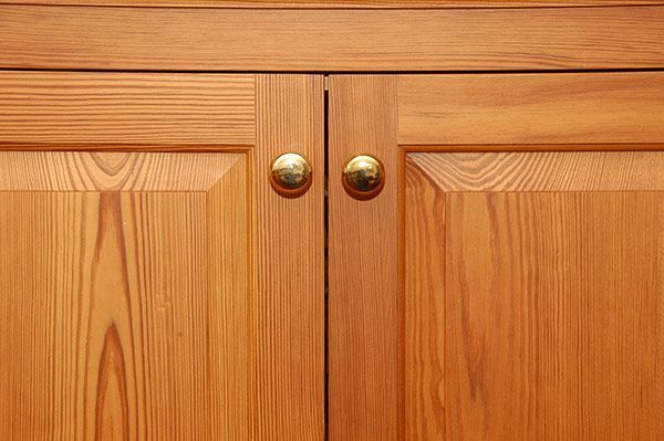 A close up of a wooden cabinet with brass handles.