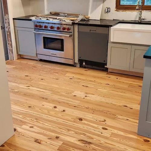 A kitchen with hardwood floors , stainless steel appliances , a stove and a sink.