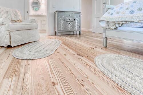 A bedroom with hardwood floors , a bed , a chair , and a rug.