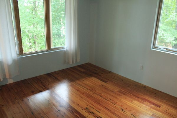 An empty room with hardwood floors and two windows.