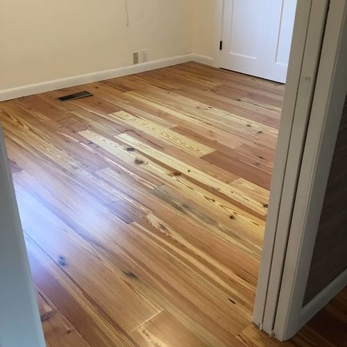A bedroom with hardwood floors and white walls.